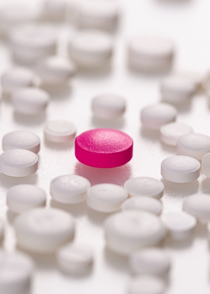 White medicinal pills with a single magenta pill in the center. Pharmacy drugstore product